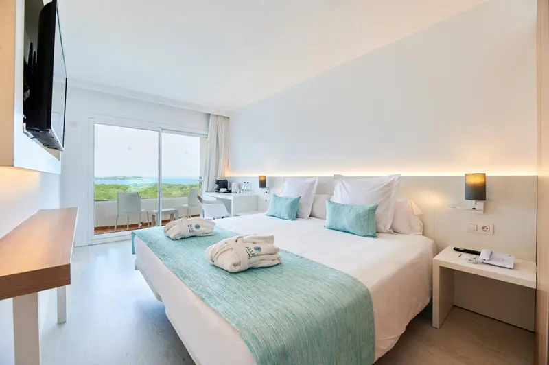 Chambre lumineuse avec un grand lit et vue sur la mer.
