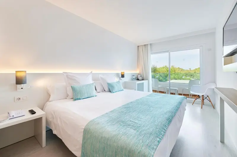 Une chambre lumineuse avec un grand lit et une vue sur la végétation.