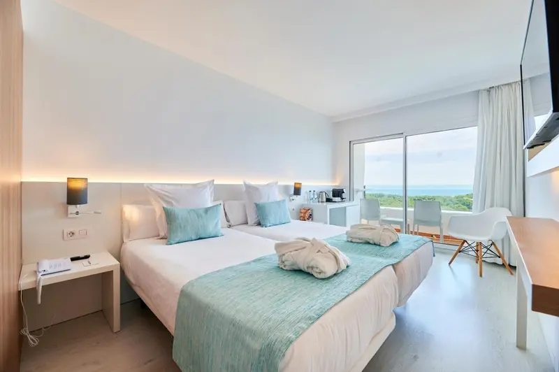 Chambre lumineuse avec un grand lit et une vue sur la mer.