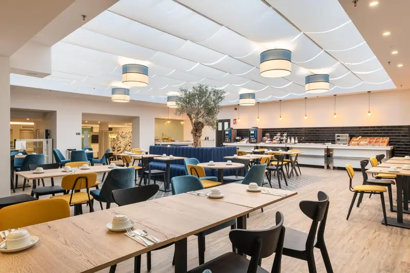 Une salle lumineuse avec des tables dressées pour le repas.