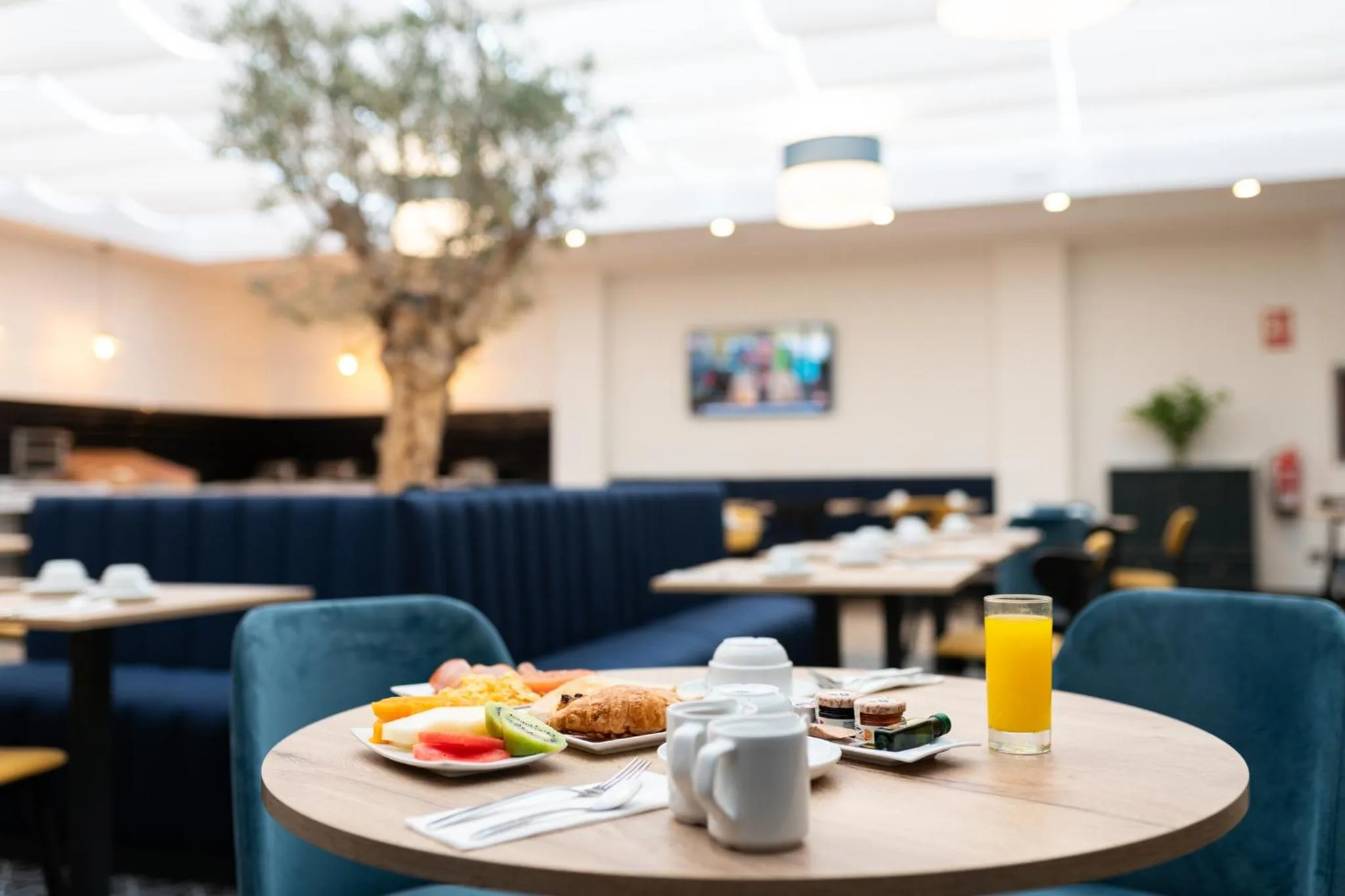 Une table est dressée avec un petit-déjeuner composé de fruits, de viennoiseries et de boissons.