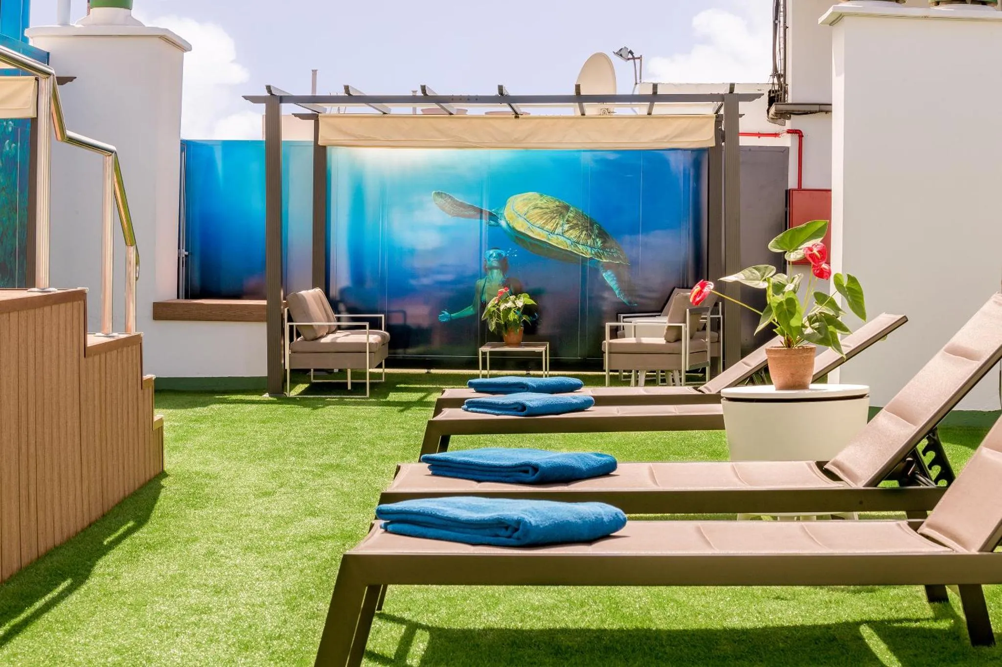 Terrasse aménagée avec des transats et des fauteuils, devant une grande image sous-marine.