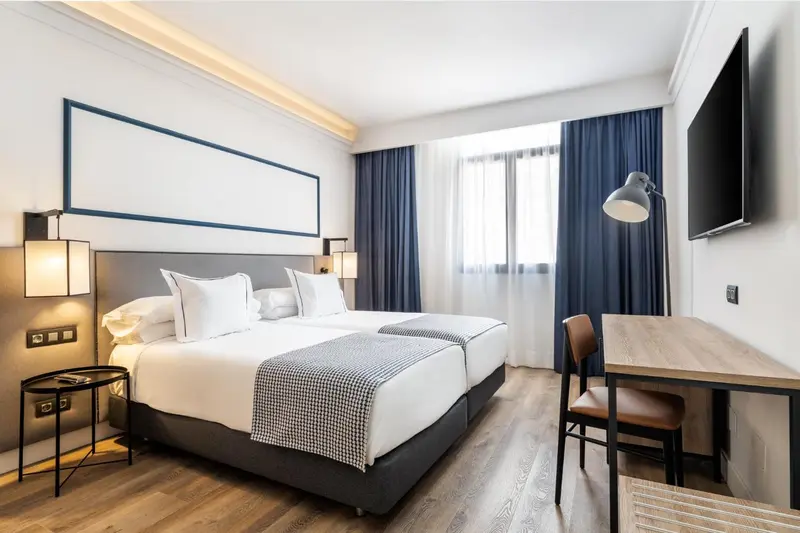 Une chambre lumineuse avec un grand lit et un bureau.