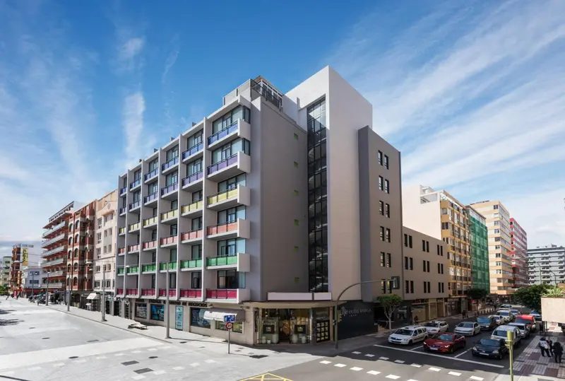 Bâtiment moderne avec des balcons colorés au bord d'une rue animée.