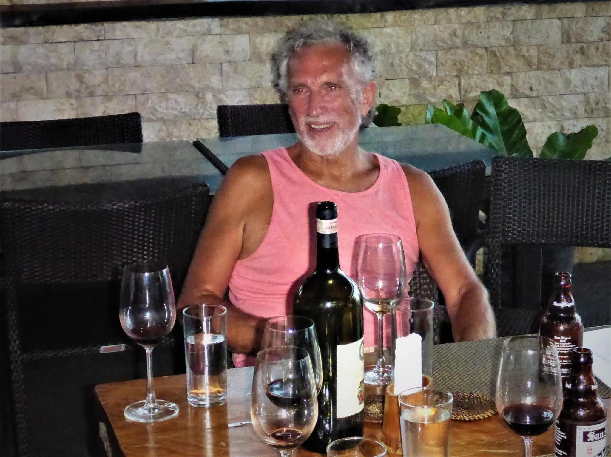 Un homme souriant est assis à une table avec des boissons.