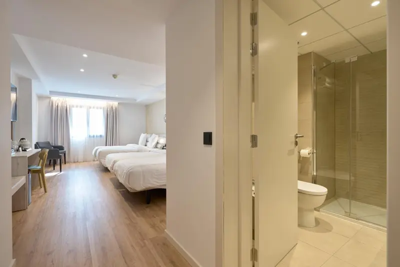 Une chambre lumineuse avec deux lits et une salle de bain attenante.