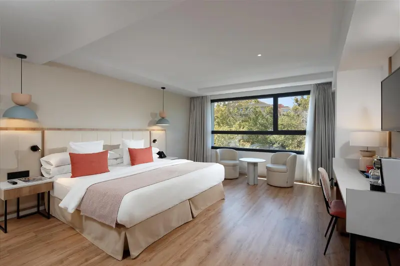Une chambre lumineuse avec un grand lit et deux fauteuils.