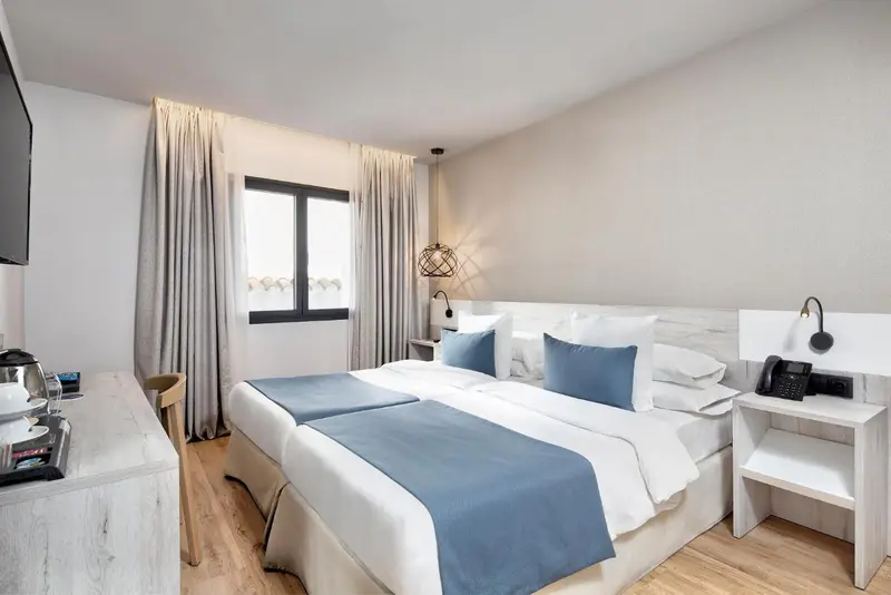 Une chambre lumineuse avec un lit double et des tables de chevet.