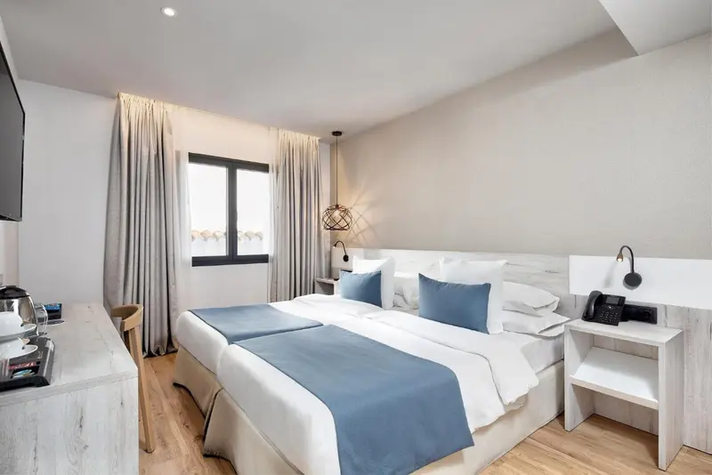 Une chambre lumineuse avec un grand lit et des tables de chevet.