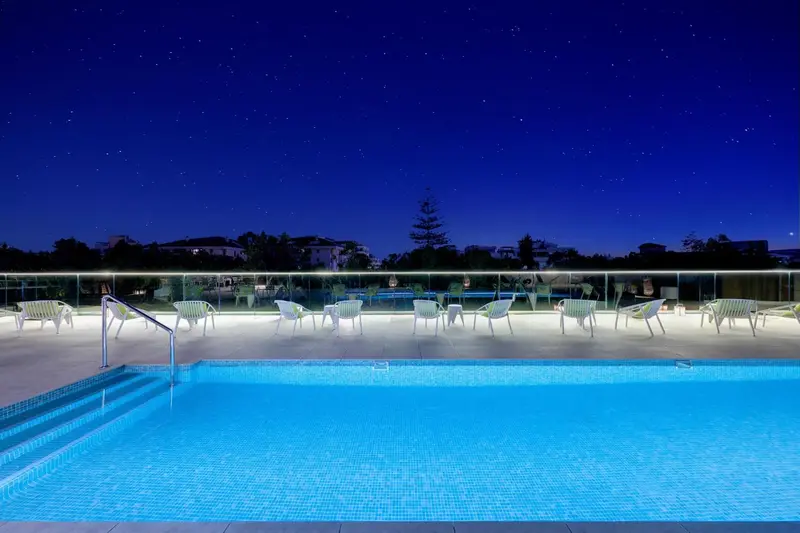 Terrasse lumineuse avec piscine éclairée sous un ciel étoilé.