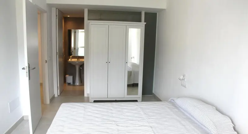 Une chambre lumineuse avec un grand lit et une armoire.