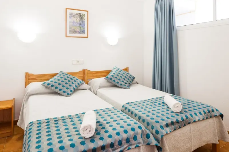 Une chambre lumineuse avec deux lits simples et une décoration sobre.
