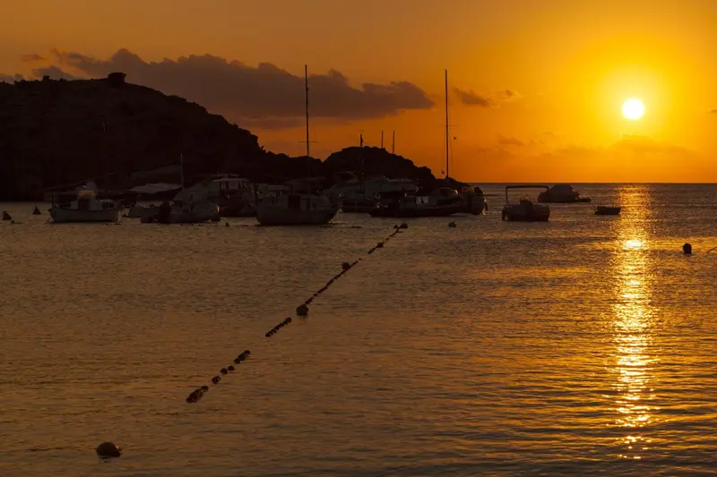 Coucher de soleil sur une baie avec des bateaux amarrés.