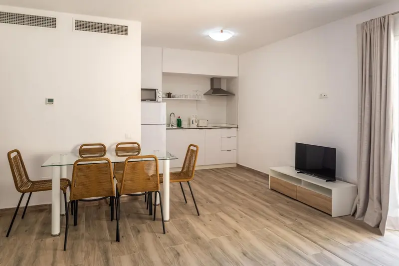 Une salle lumineuse avec un coin repas et une kitchenette.