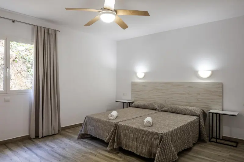 Une chambre lumineuse avec un lit double et des appliques murales.