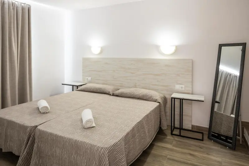 Une chambre avec un grand lit et un miroir.