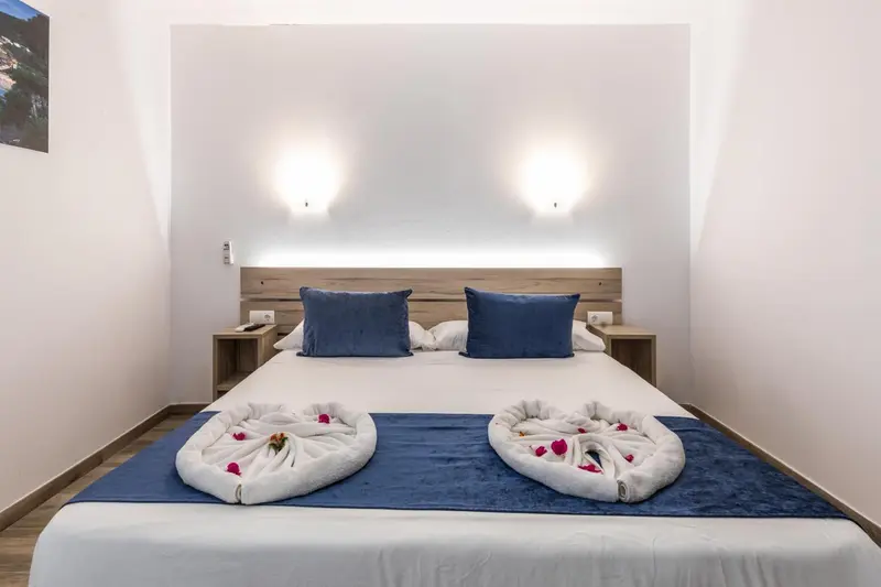 Une chambre lumineuse avec un grand lit et une décoration florale sur le drapé.