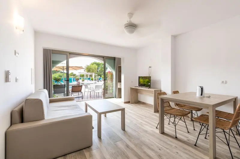 Espace de vie lumineux avec canapé et table à manger près d'une baie vitrée.
