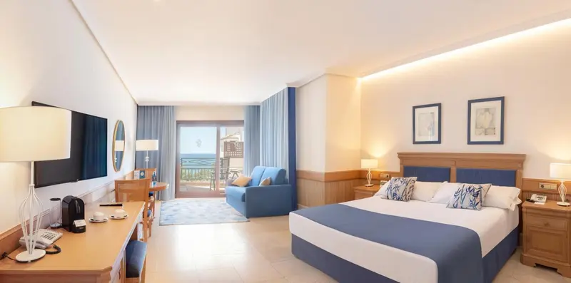 Une chambre lumineuse avec un lit double et un coin salon.