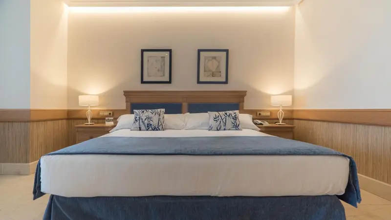 Une chambre avec un grand lit recouvert d'une courtepointe bleue et de coussins décoratifs.
