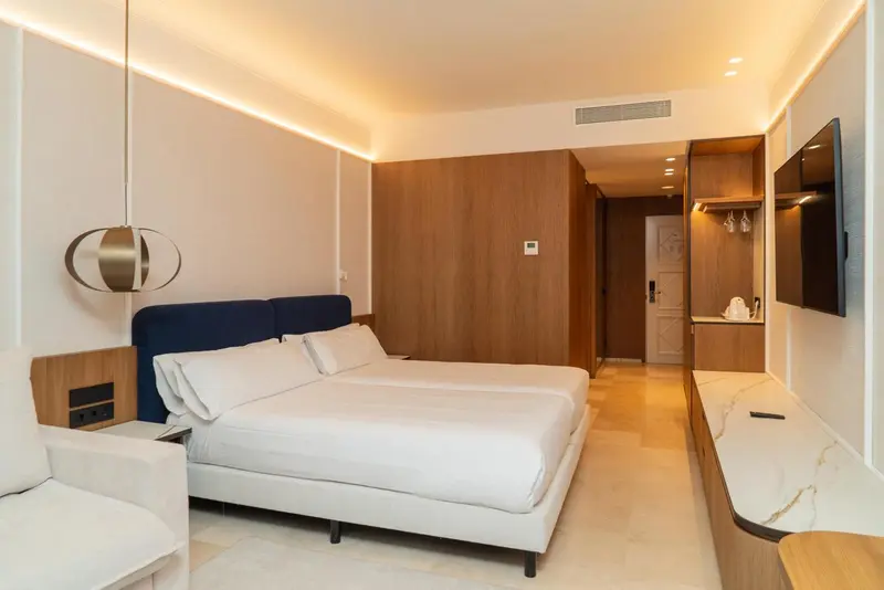 Une chambre lumineuse avec un grand lit et un téléviseur mural.