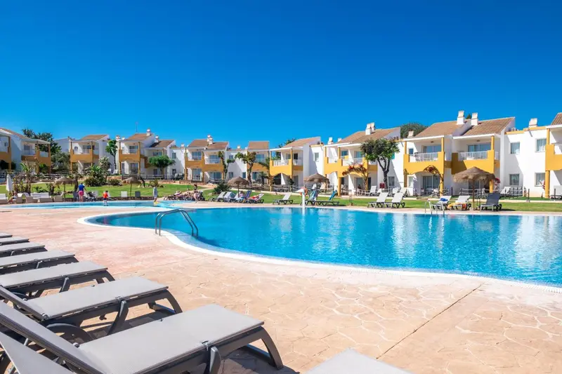 Transats alignés au bord d'une piscine turquoise dans un complexe hôtelier.