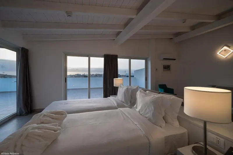 Chambre lumineuse avec un grand lit donnant sur une vue mer.