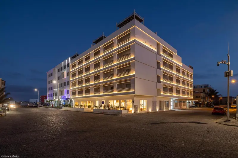 Bâtiment moderne éclairé la nuit avec des rangées de balcons.