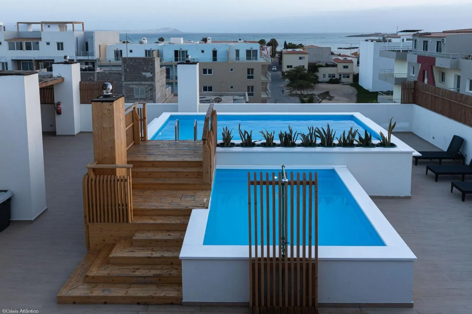 Terrasse avec deux piscines rectangulaires et mobilier de détente.