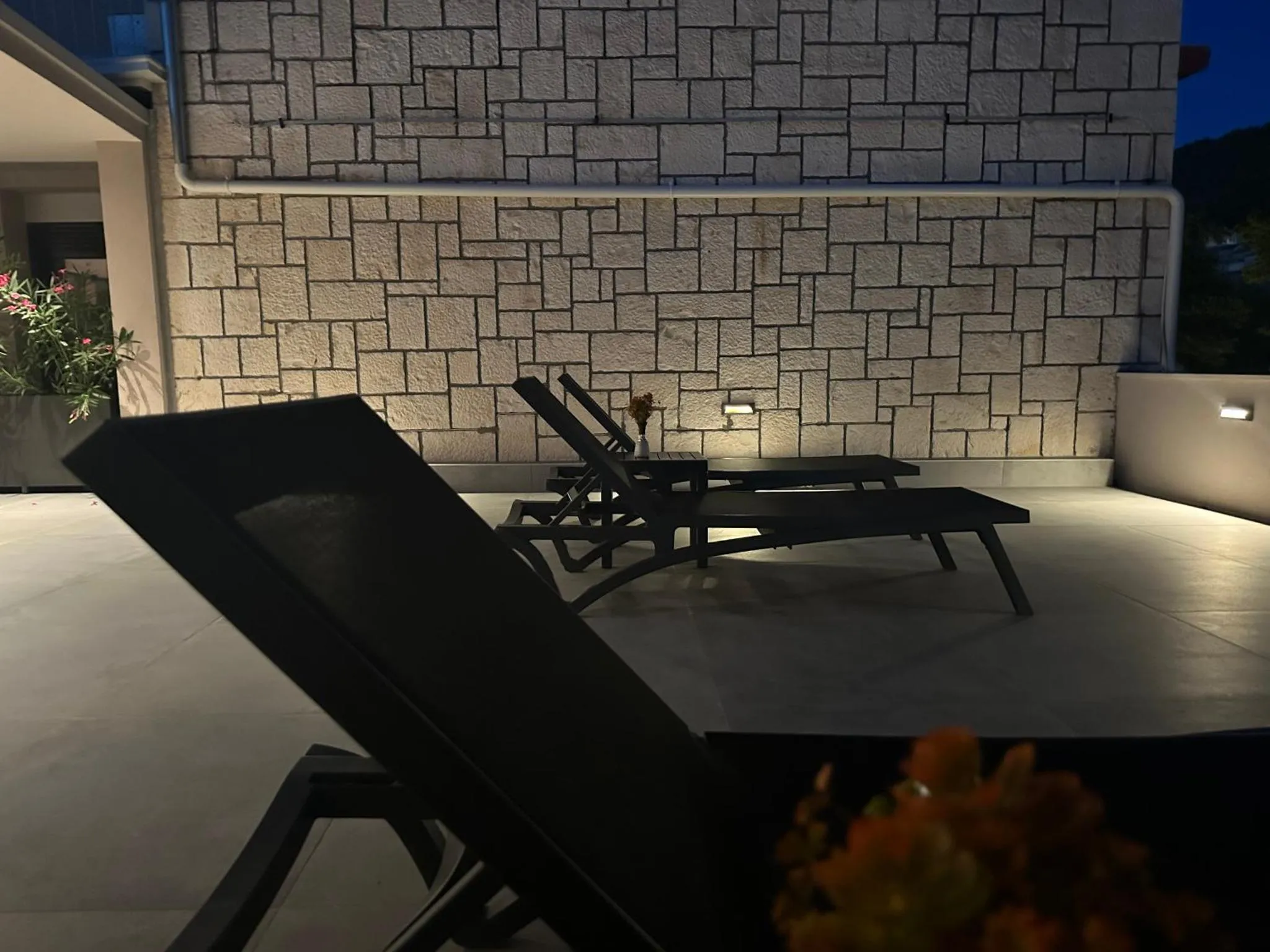 Transats noirs sur une terrasse éclairée la nuit.