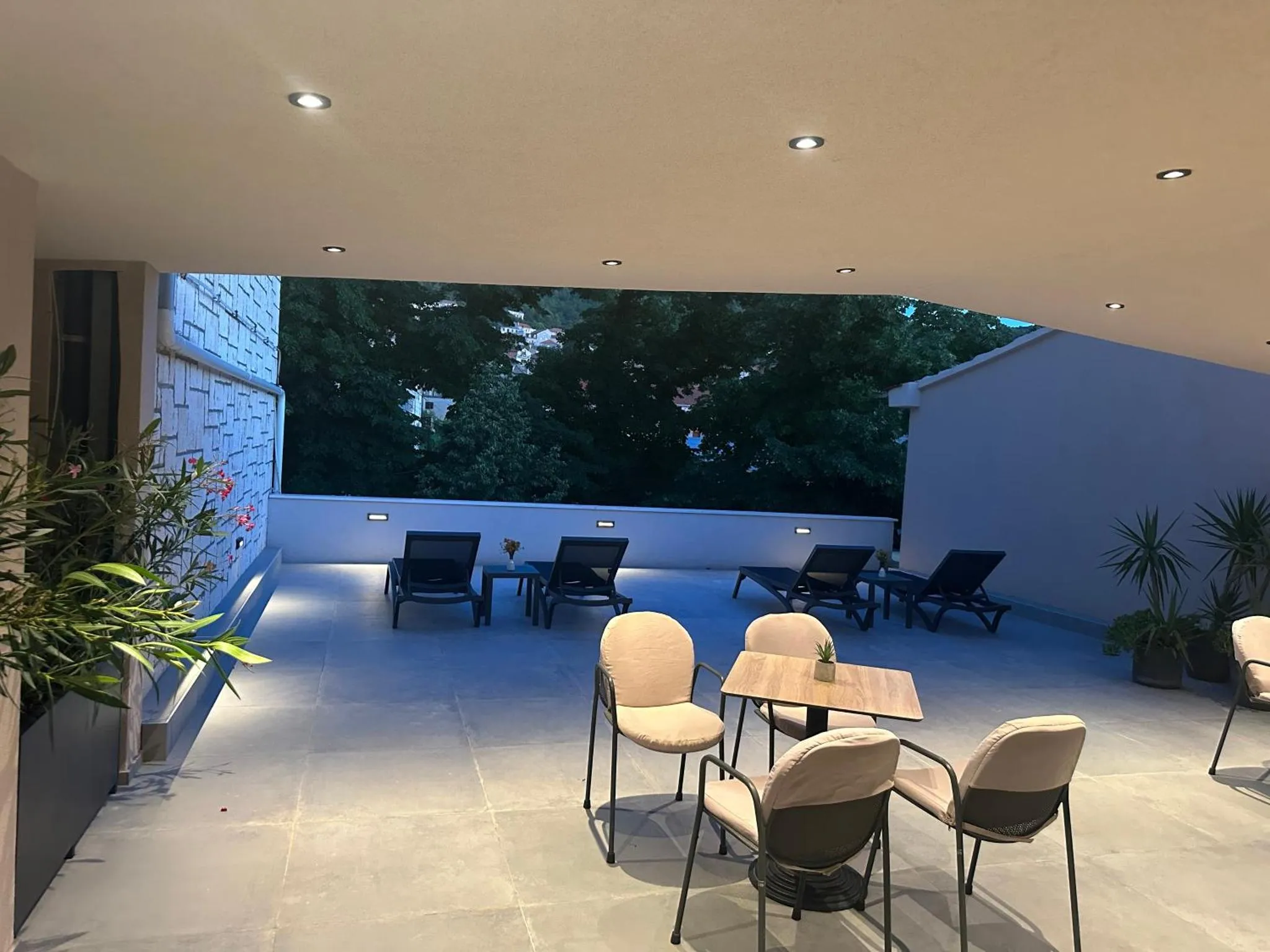 Terrasse aménagée avec tables, chaises et transats sous un éclairage tamisé.