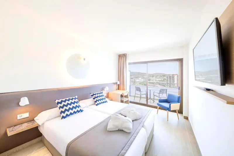 Une chambre lumineuse avec un lit double et un accès à un balcon.