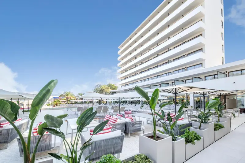 Terrasse aménagée avec des salons et des transats près d'une piscine.