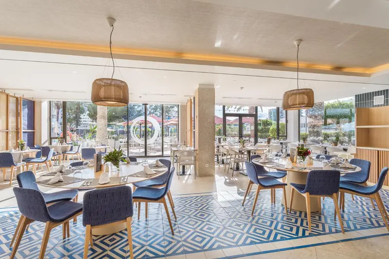 Une salle lumineuse avec des tables dressées pour un repas.