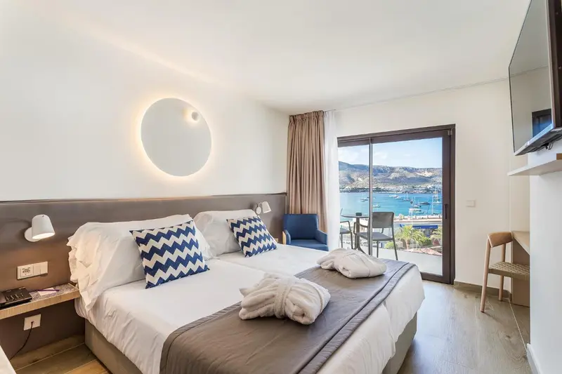 Chambre lumineuse avec un grand lit et une vue sur la mer.