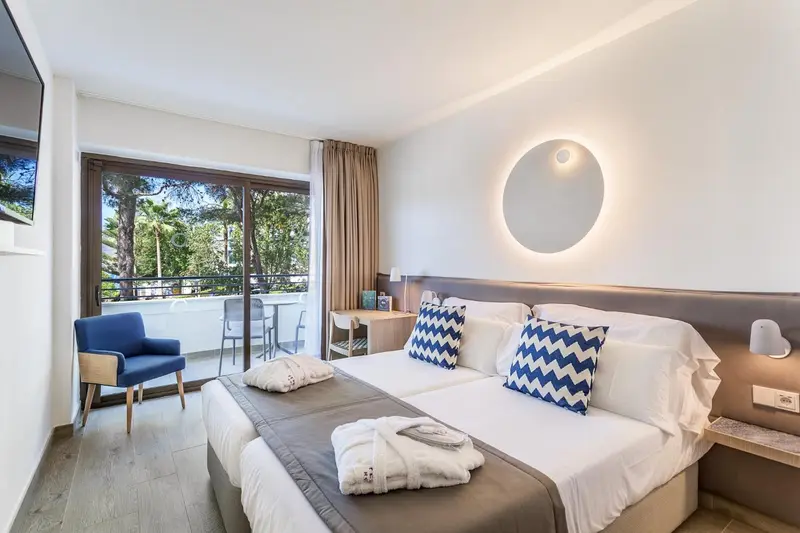 Chambre lumineuse avec un grand lit et un accès à un balcon.
