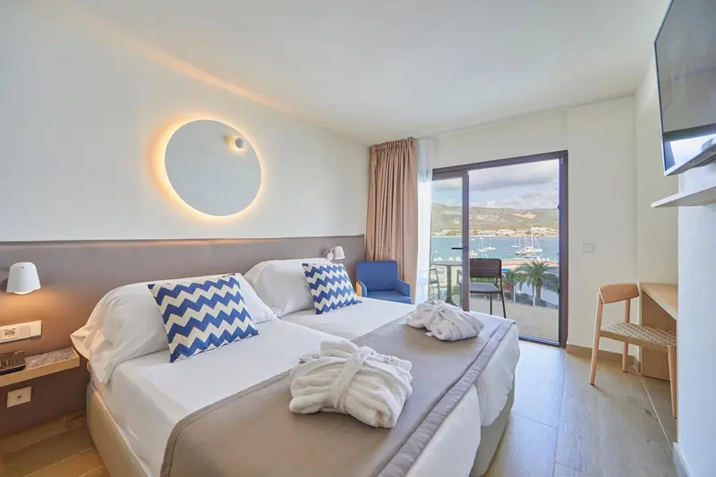 Une chambre lumineuse avec un grand lit et une vue sur le port.