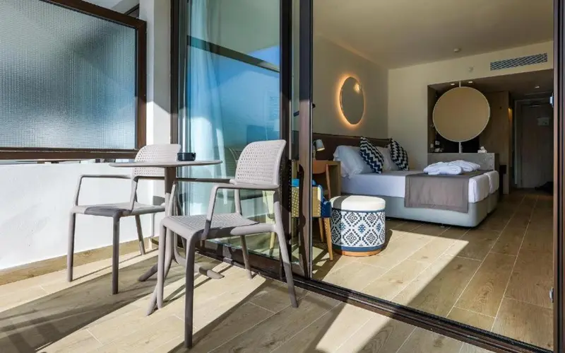 Espace extérieur aménagé avec table et chaises devant une chambre lumineuse.