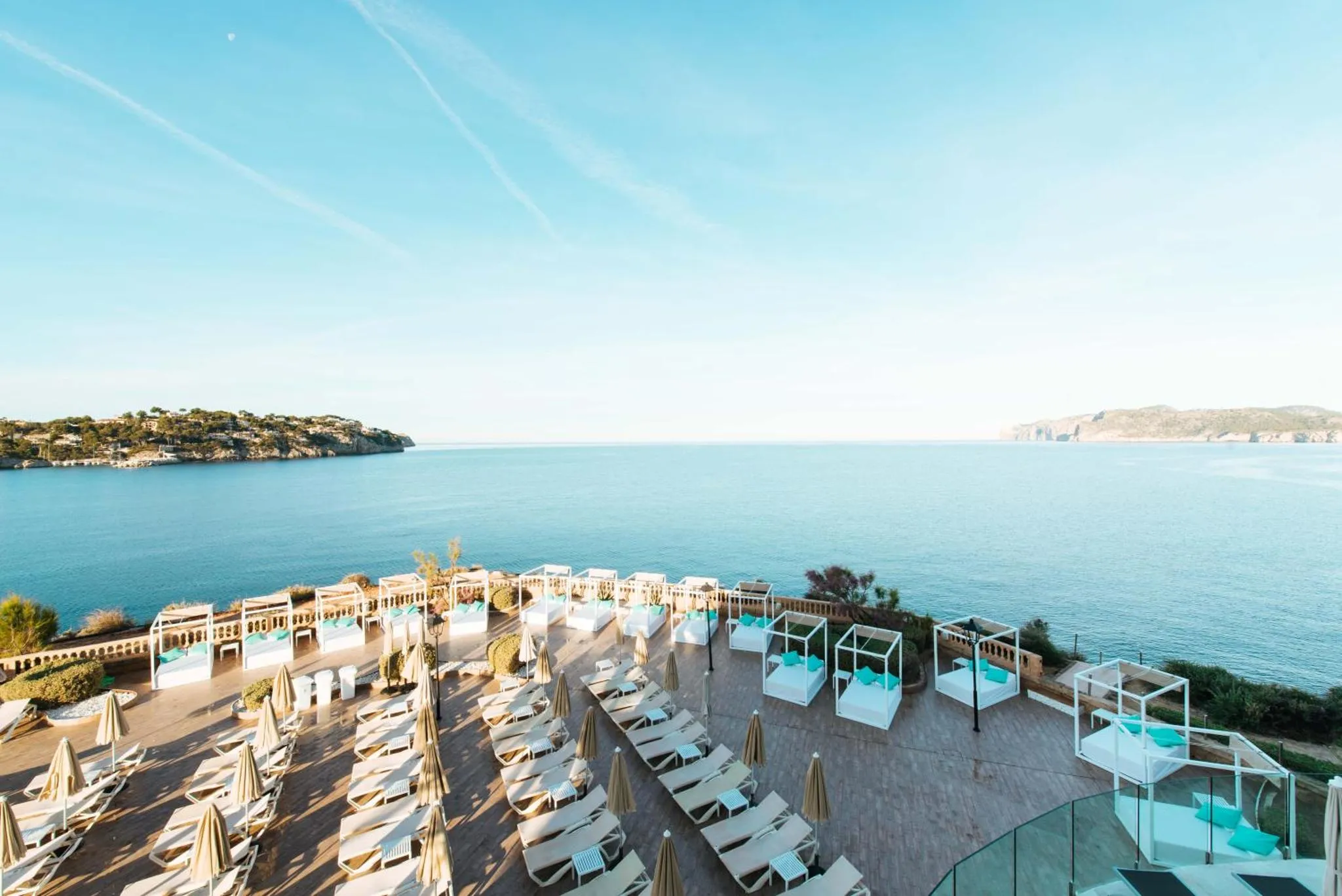 Terrasse avec transats blancs et vue sur la mer.