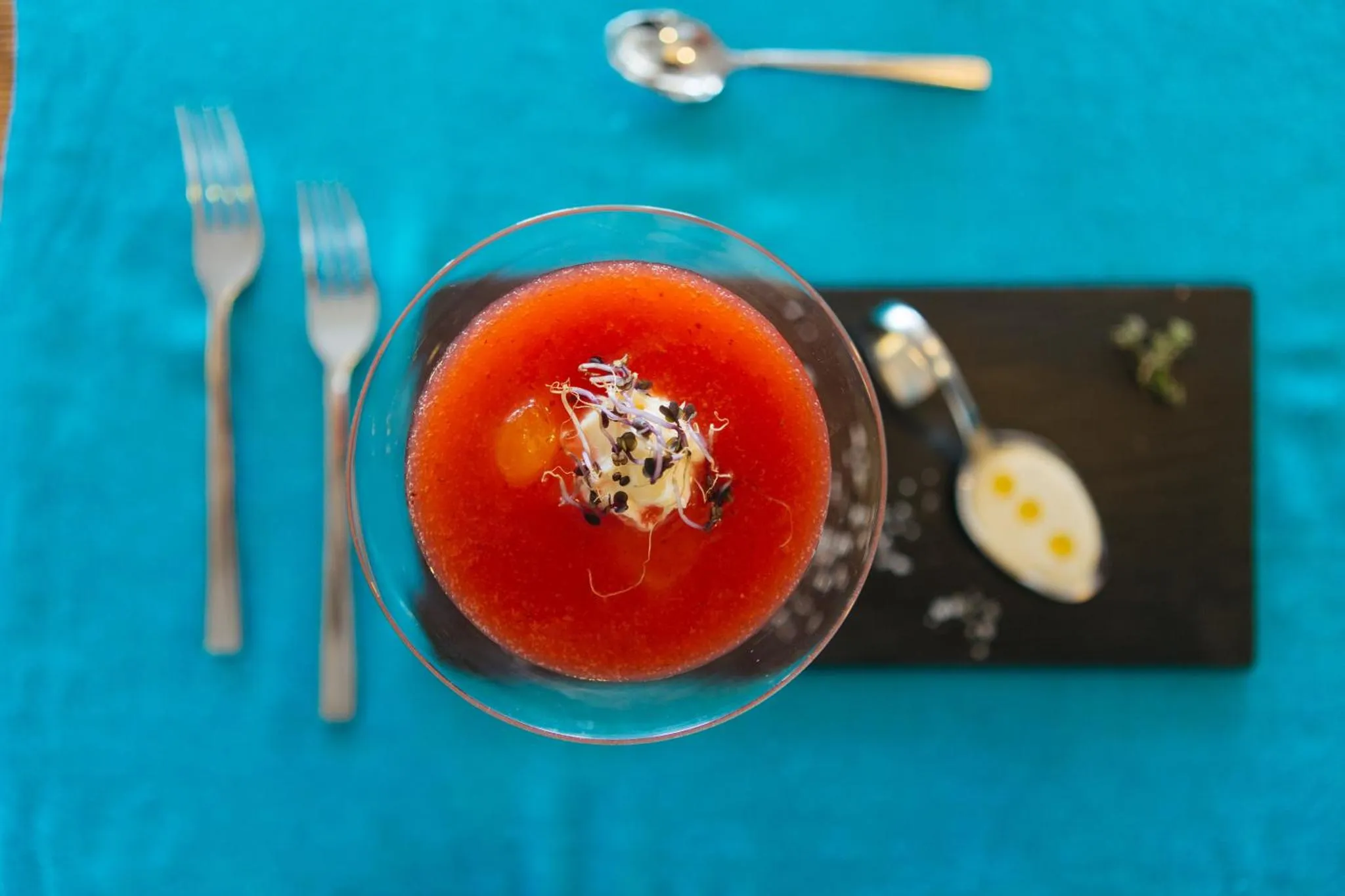 Présentation d'un plat raffiné avec une soupe froide et des accompagnements.