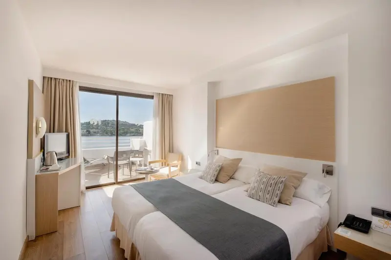 Chambre lumineuse avec un grand lit et une vue sur la mer.
