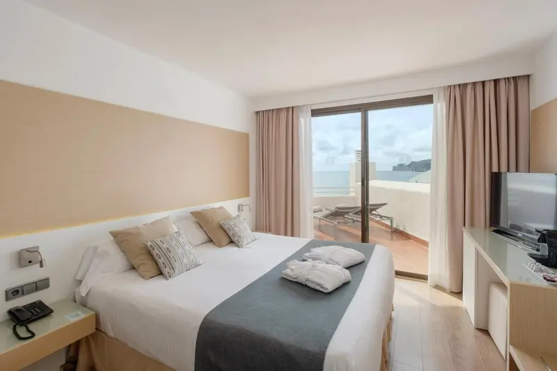 Une chambre lumineuse avec un grand lit et un accès à une terrasse.