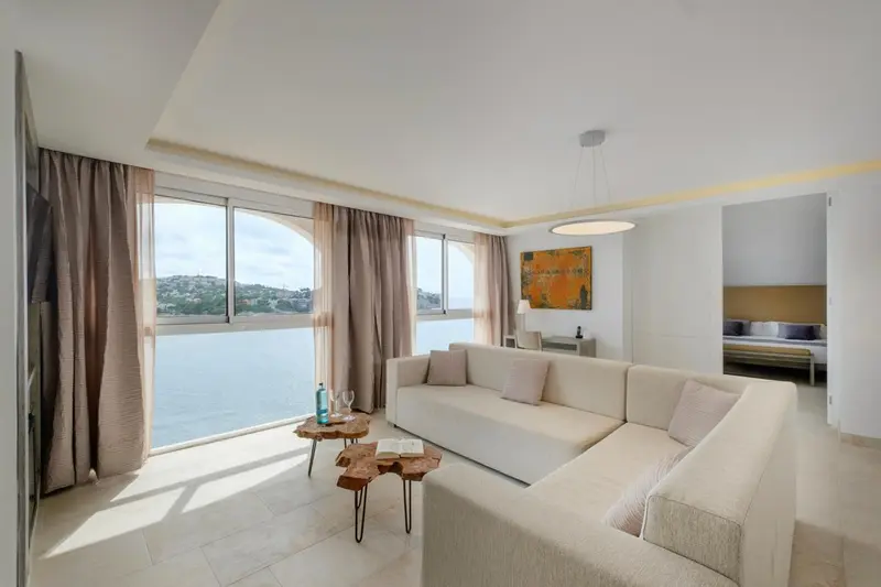 Espace de séjour lumineux avec canapé et vue sur la mer.
