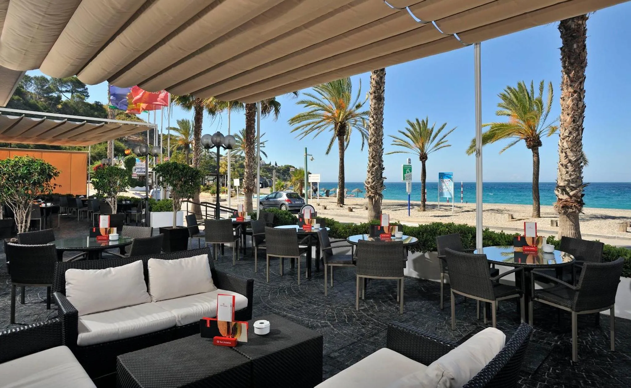 Terrasse ombragée avec mobilier de détente et vue sur la mer.