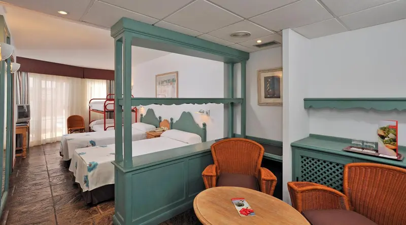 Chambre avec lits jumeaux et mobilier en rotin.
