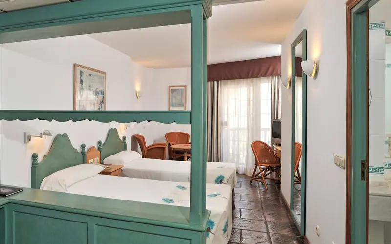 Une chambre lumineuse avec deux lits et un coin repas.