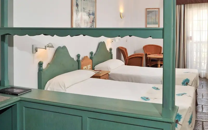 Une chambre lumineuse avec deux lits simples et un coin repas.