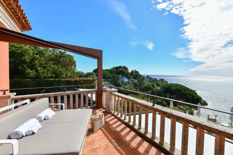 Terrasse carrelée avec transats et vue sur la mer.