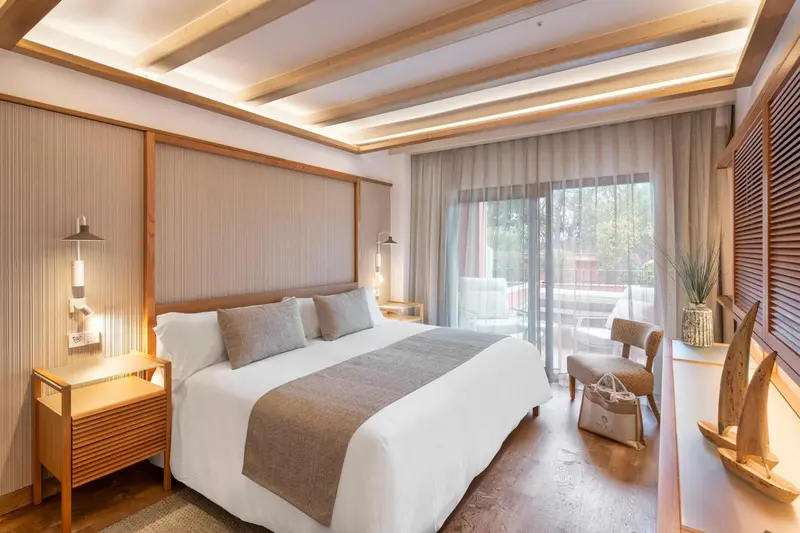 Une chambre lumineuse avec un grand lit et un fauteuil.