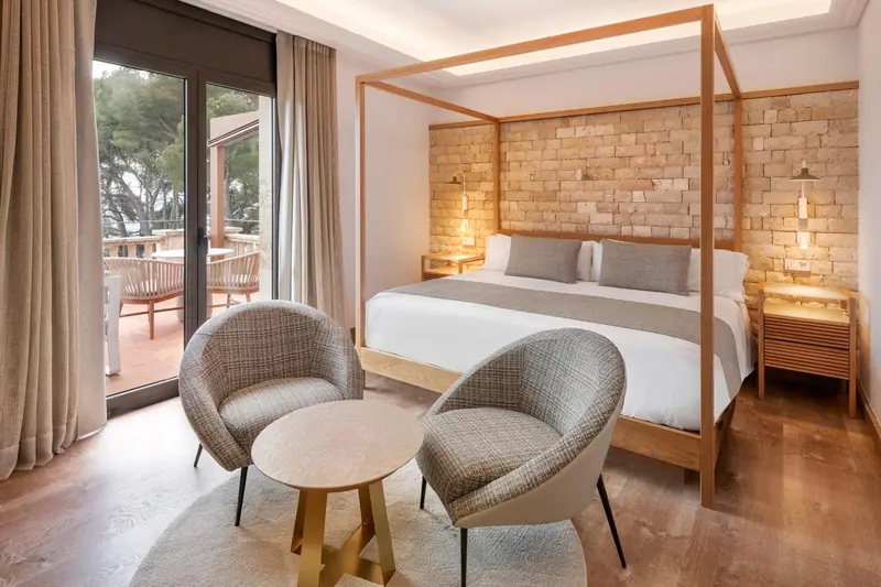 Chambre lumineuse avec un grand lit et un coin salon.